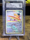 A graded Pokémon Dragonite trading card inside a clear plastic protective slab, with the grading label visible at the top. The card is photographed standing on a small clear display stand on a wooden surface.