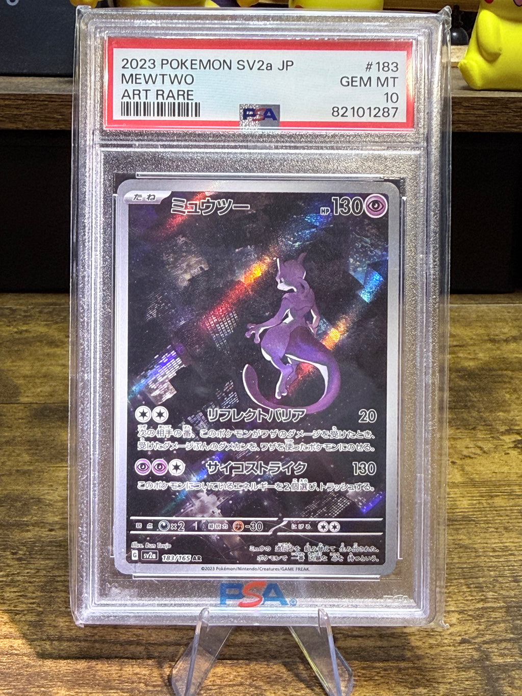 A graded Pokémon card of Mewtwo from 2023, showing the Art Rare version. The card is encapsulated in a PSA grading holder and displayed on a clear stand on a wooden surface.
